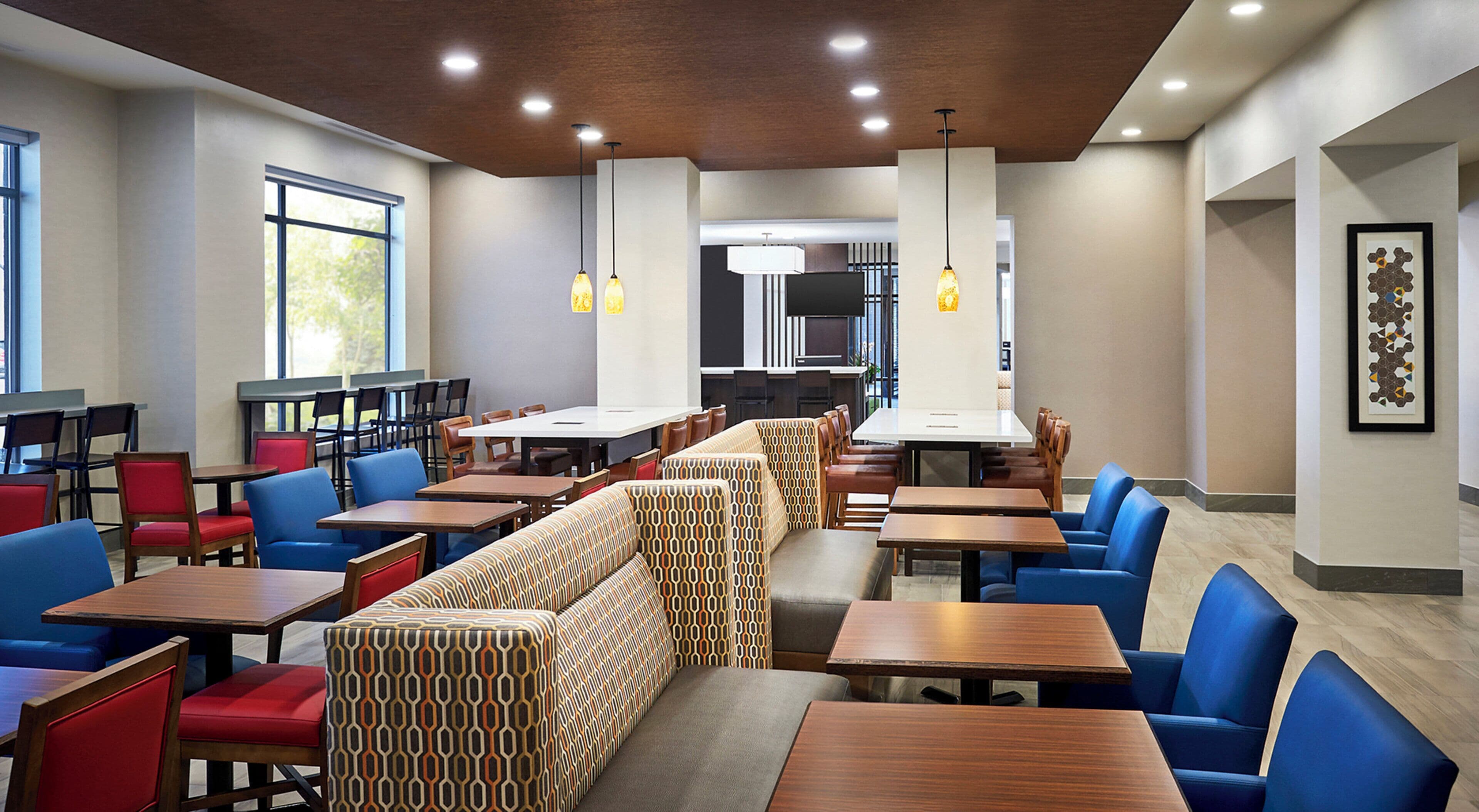 Een modern restaurantinterieur met hoge tafels, zitjes en verschillende zitmogelijkheden.
