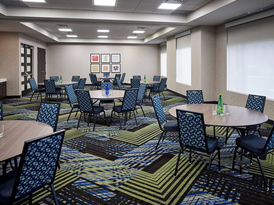 A conference room with multiple tables and chairs, a patterned carpet, and framed artwork on the wall.