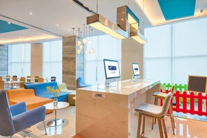 Un espace d’accueil moderne doté d’un comptoir en marbre, de sièges confortables et d’écrans numériques.