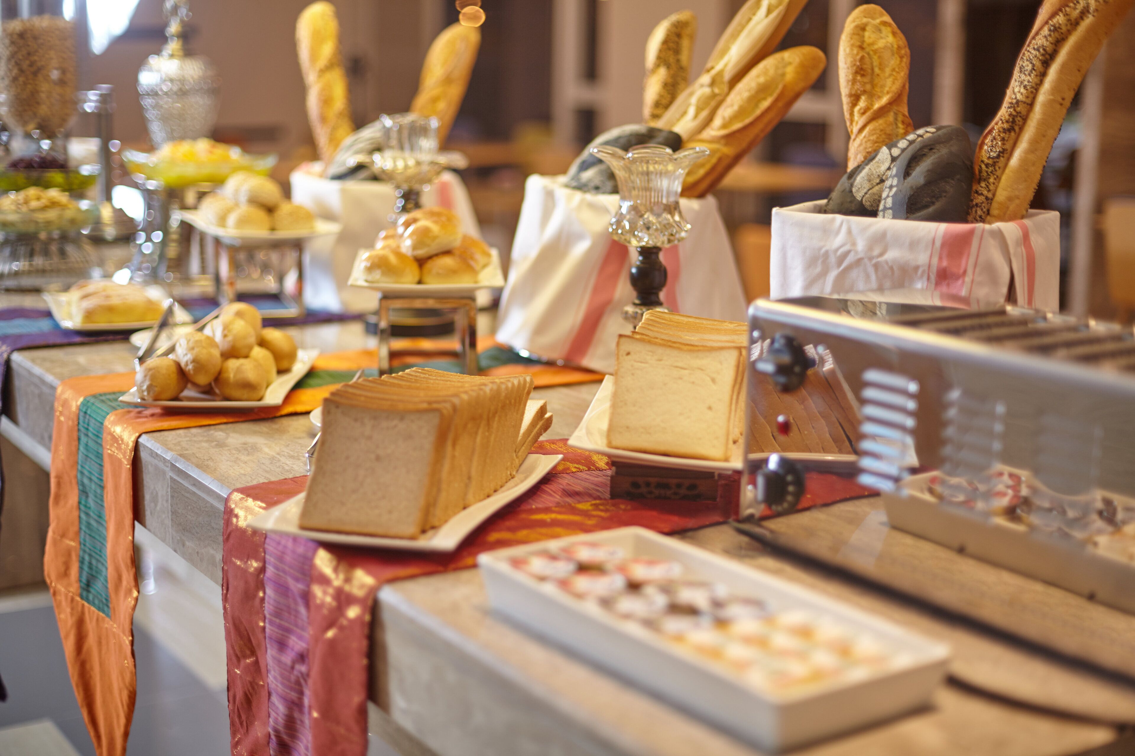 A buffet table with various food items including bread, pastries, and a cake.