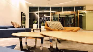 A modern lobby with a blue sofa, an orange chair, and a round table.