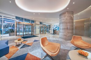 A modern lobby with a reception desk, seating area, and a large pillar. - Holiday Inn Express Hangzhou Gongshu by IHG (Hangzhou)