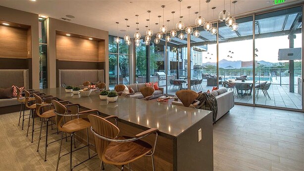 Une cuisine moderne dotée d’un grand îlot central, de tabourets de bar et offrant une vue sur la terrasse extérieure.