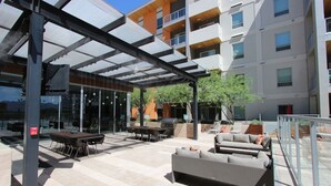 Un espace extérieur aménagé en terrasse, doté d’un coin salon abrité, d’un barbecue et d’un espace clos par des parois de verre.