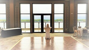 Une pièce spacieuse avec de grandes fenêtres, une scène et une table sur laquelle est posé un gâteau.