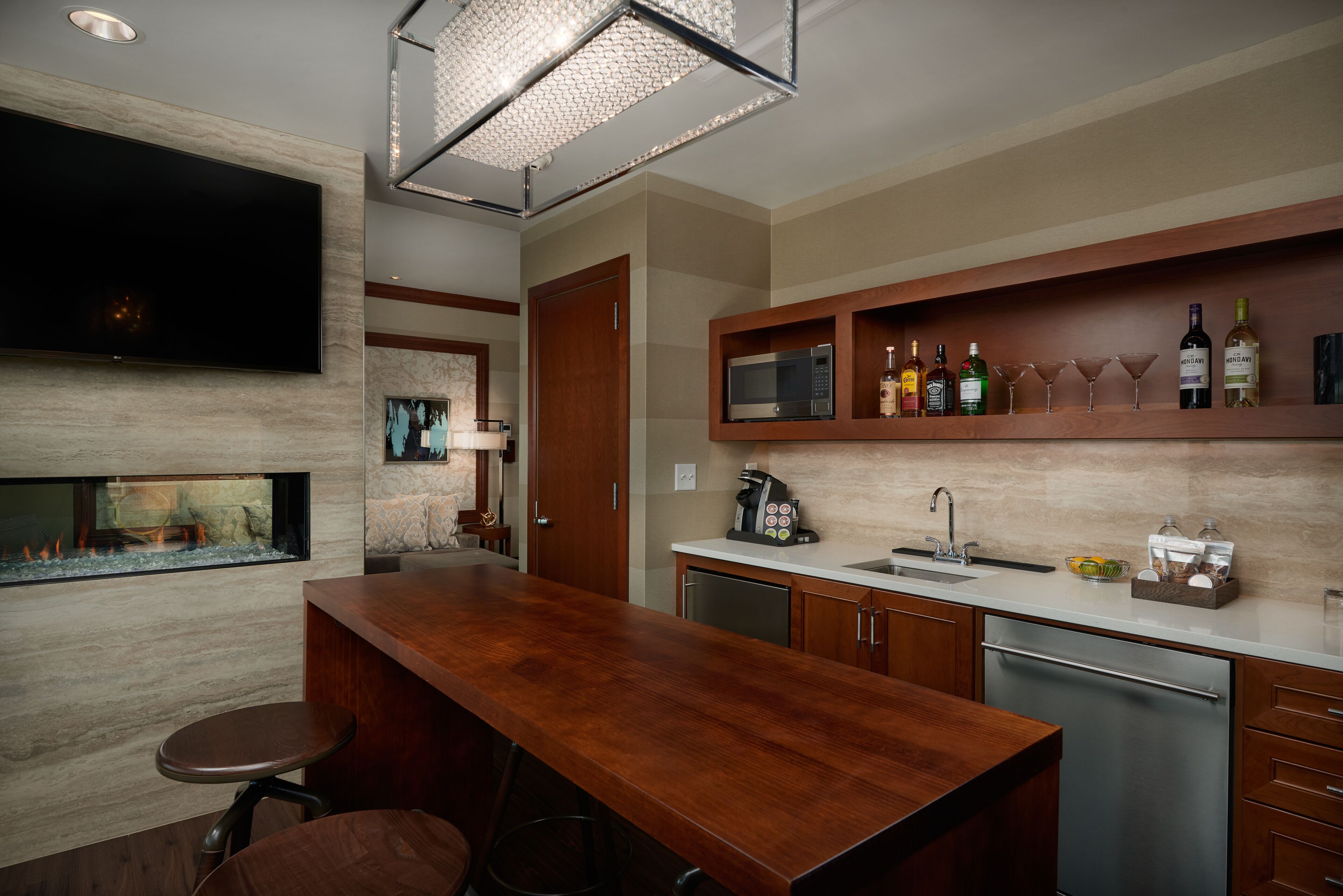 Una cocina moderna con barra de madera, televisor de pantalla plana, microondas integrado y espacio para vinos.