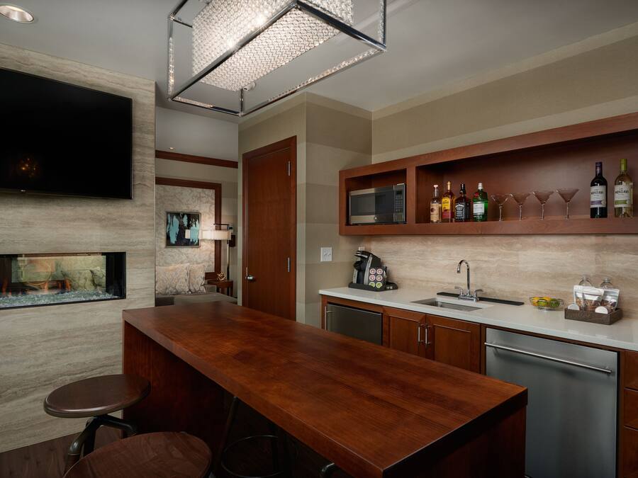 Una cocina moderna con barra de madera, televisor de pantalla plana, microondas integrado y espacio para vinos.