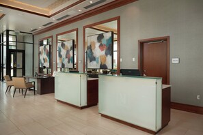 A reception area with glass-fronted desks, a wooden floor, and a "Hotel Office" sign on the wall. - The Merrill Hotel, Muscatine, a Tribute Portfolio Hotel (Muscatine)