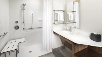 A modern bathroom with a shower, a sink, a mirror, and a towel rack.