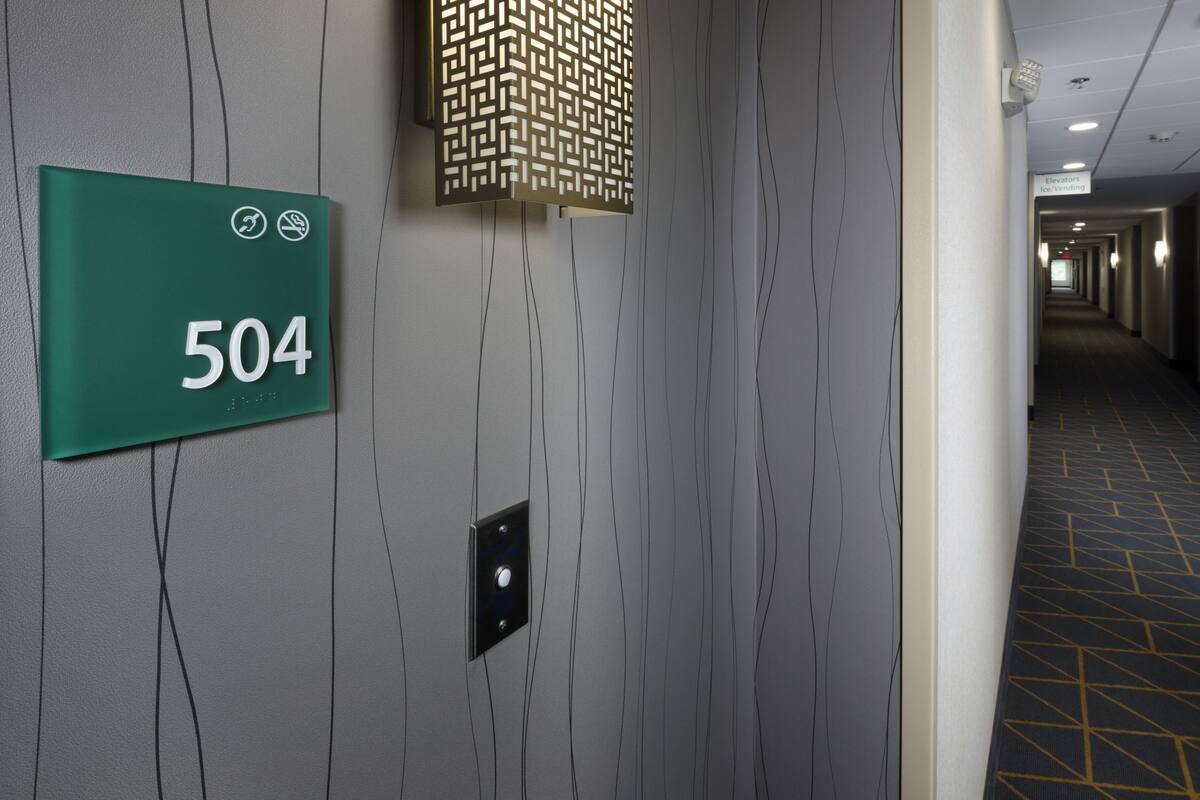 Un couloir avec un panneau vert indiquant le numéro de la pièce 504, un luminaire au motif décoratif et un sol à motifs.