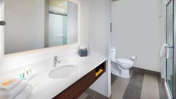 Un baño moderno con un espejo grande, un lavabo, un inodoro y una zona de ducha.