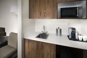 A kitchenette with a microwave, coffee maker, and two containers on the counter. - Holiday Inn & Suites Arden - Asheville Airport by IHG (Arden)