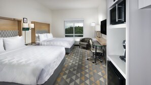 A hotel room with two beds, a desk with a chair, a television, and a window with a view of trees. - Holiday Inn & Suites Arden - Asheville Airport by IHG (Arden)