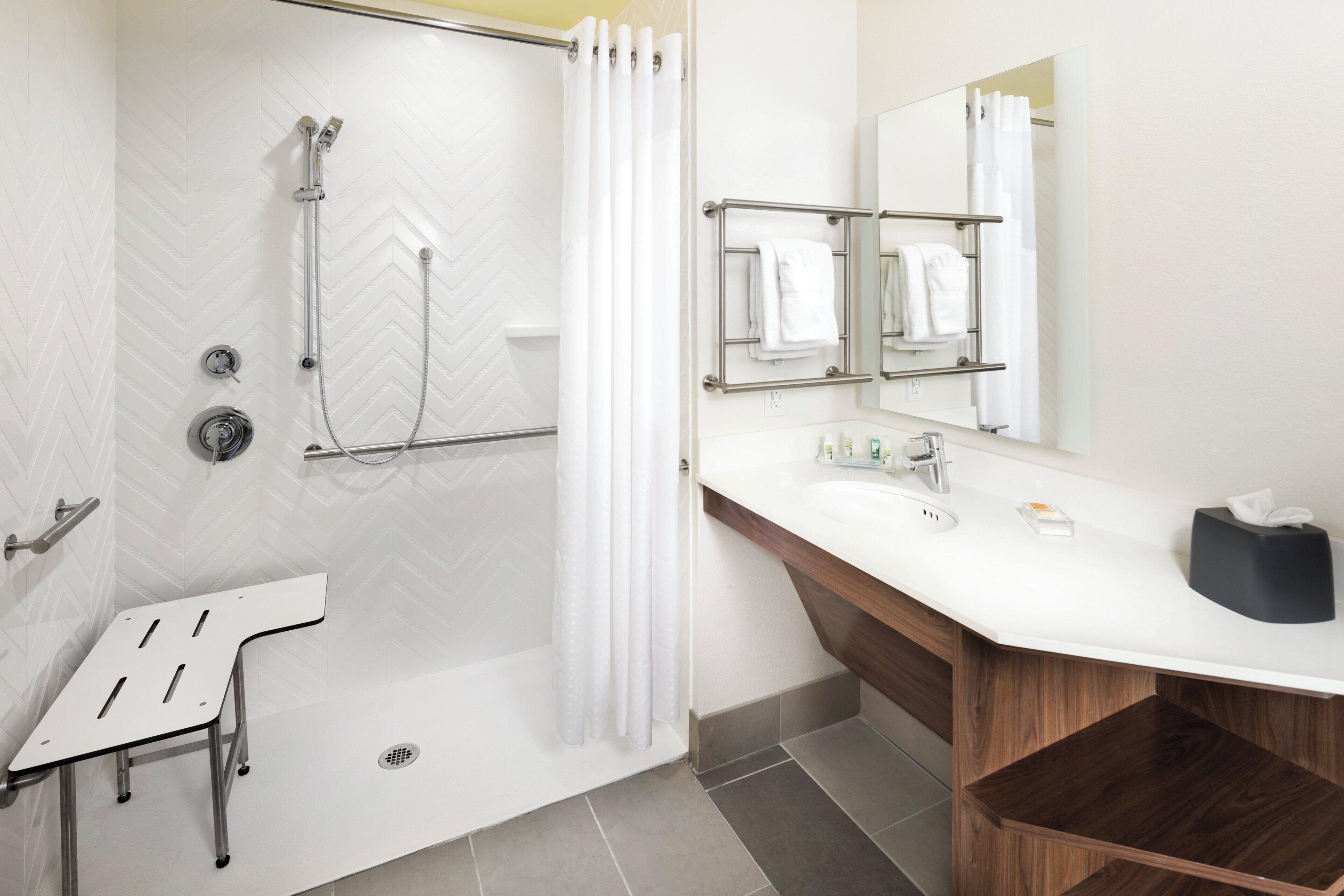 A modern bathroom with a shower, a sink with a mirror, and a towel rack.