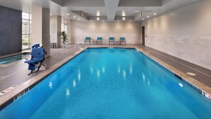An indoor swimming pool with clear lane markings, a changing room with blue chairs, and a reception area with a potted plant. - Holiday Inn & Suites Arden - Asheville Airport by IHG (Arden)