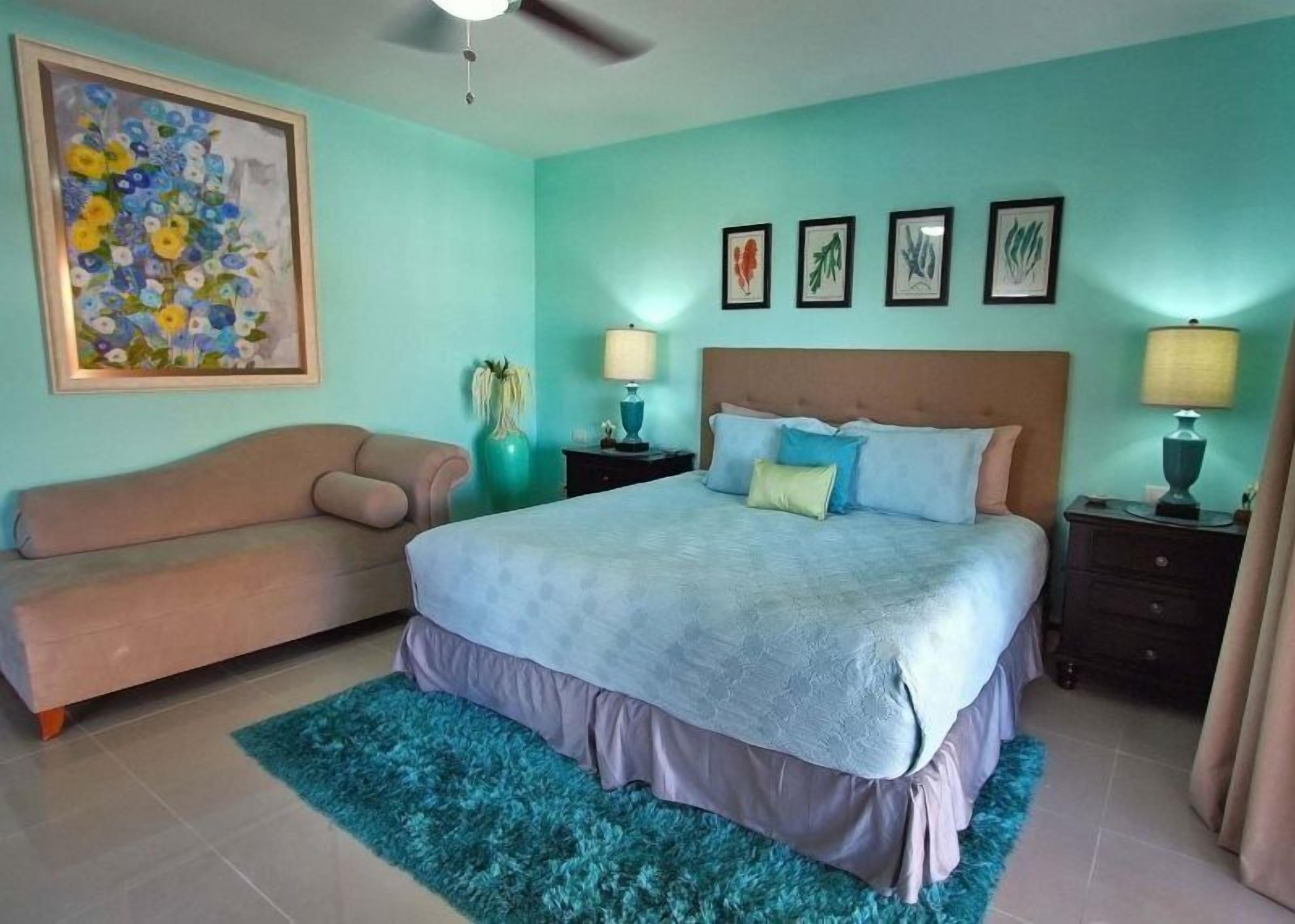 Un dormitorio con una cama, un sofá y un ventilador de techo.