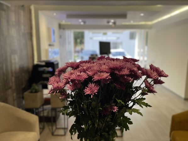 Ein Strauß rosa Blumen in einer Vase auf einem Tisch in einem modernen, gut beleuchteten Raum mit einem sichtbaren Durchgang zu einem weiteren Bereich.