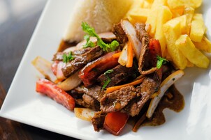 Un plato de salteado de carne con verduras y acompañamientos de arroz y mango.