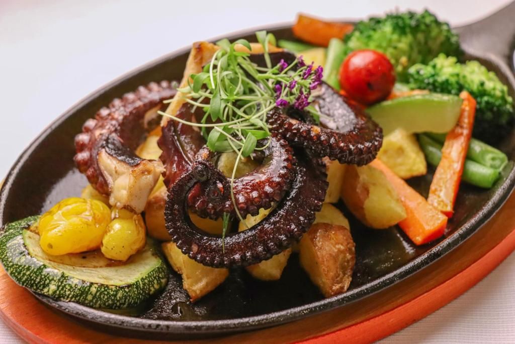 A plate of food with octopus, potatoes, and vegetables.