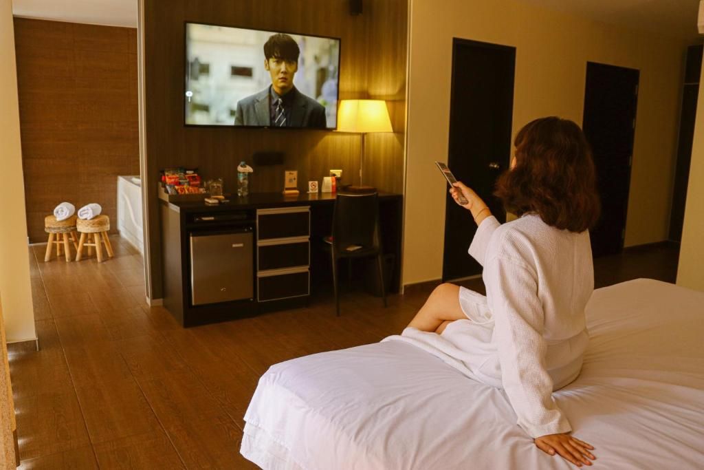 A hotel room with a bed, a desk, a television, and a lamp.