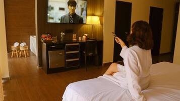 A hotel room with a bed, a desk, a television, and a lamp.