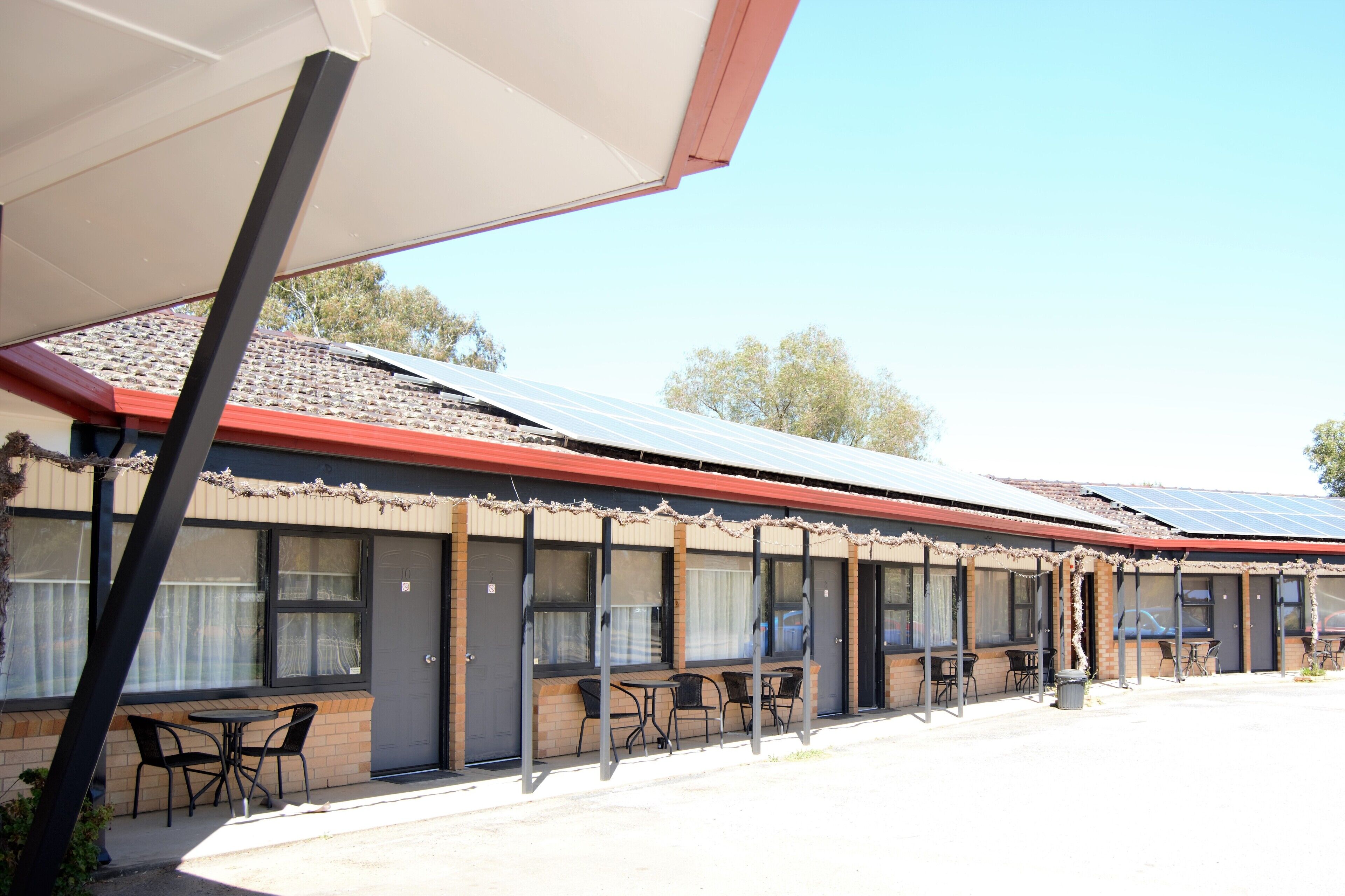 A motel with outdoor seating, a covered patio, and solar panels on the roof.