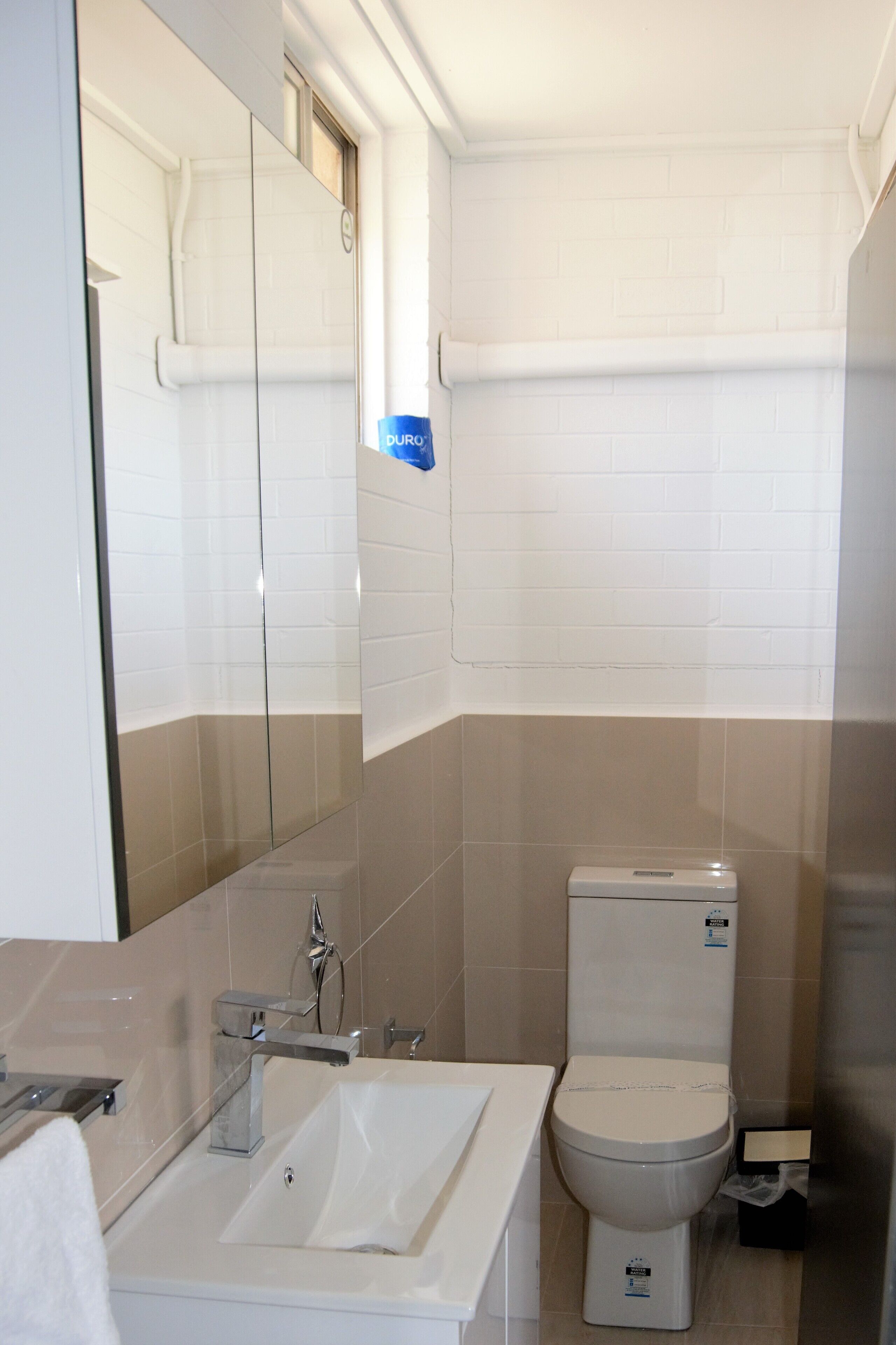 A bathroom with a white sink, mirror, and toilet.