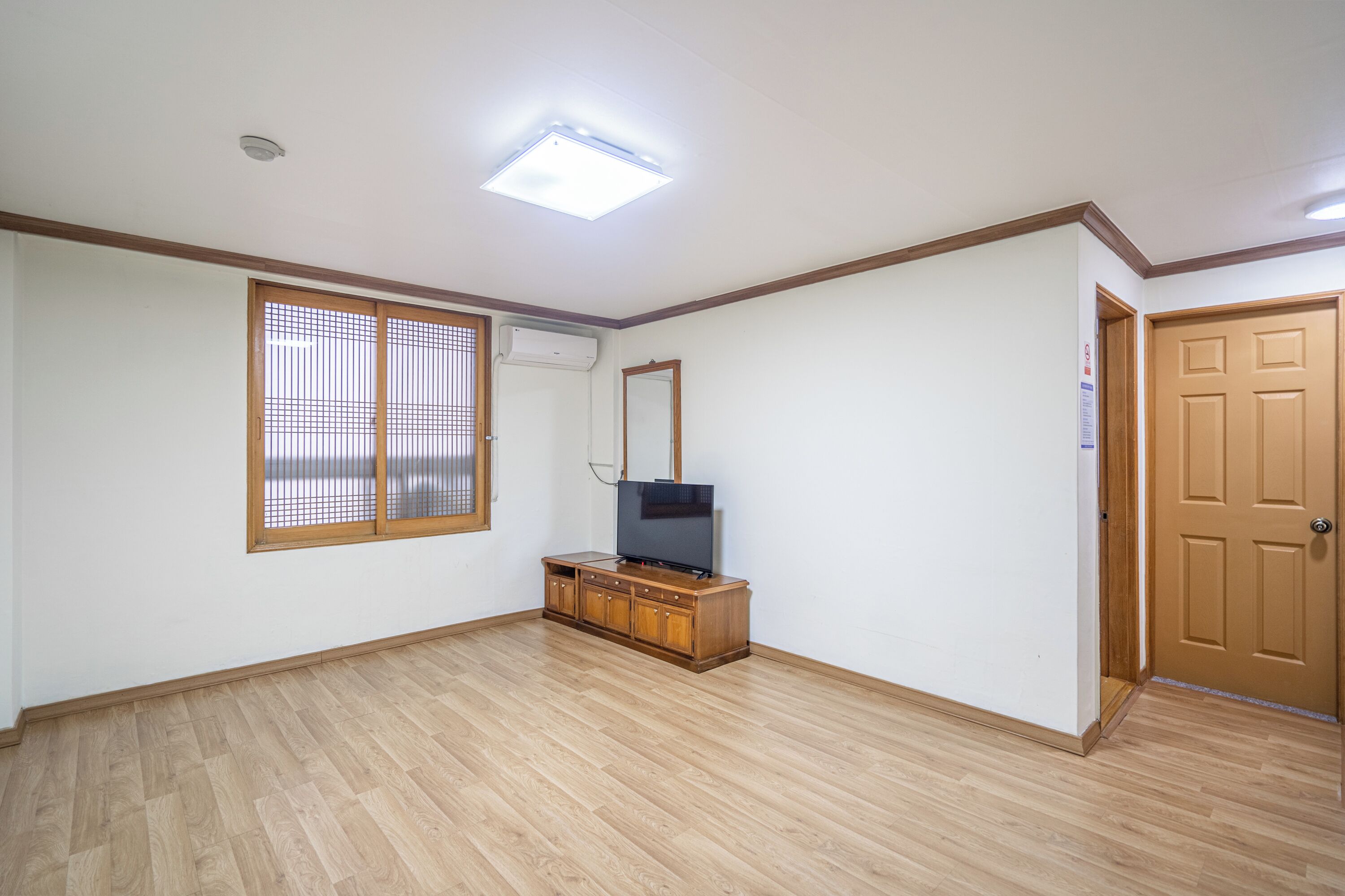 A room with a wooden cabinet, a television, a sliding glass door, and a ceiling light.