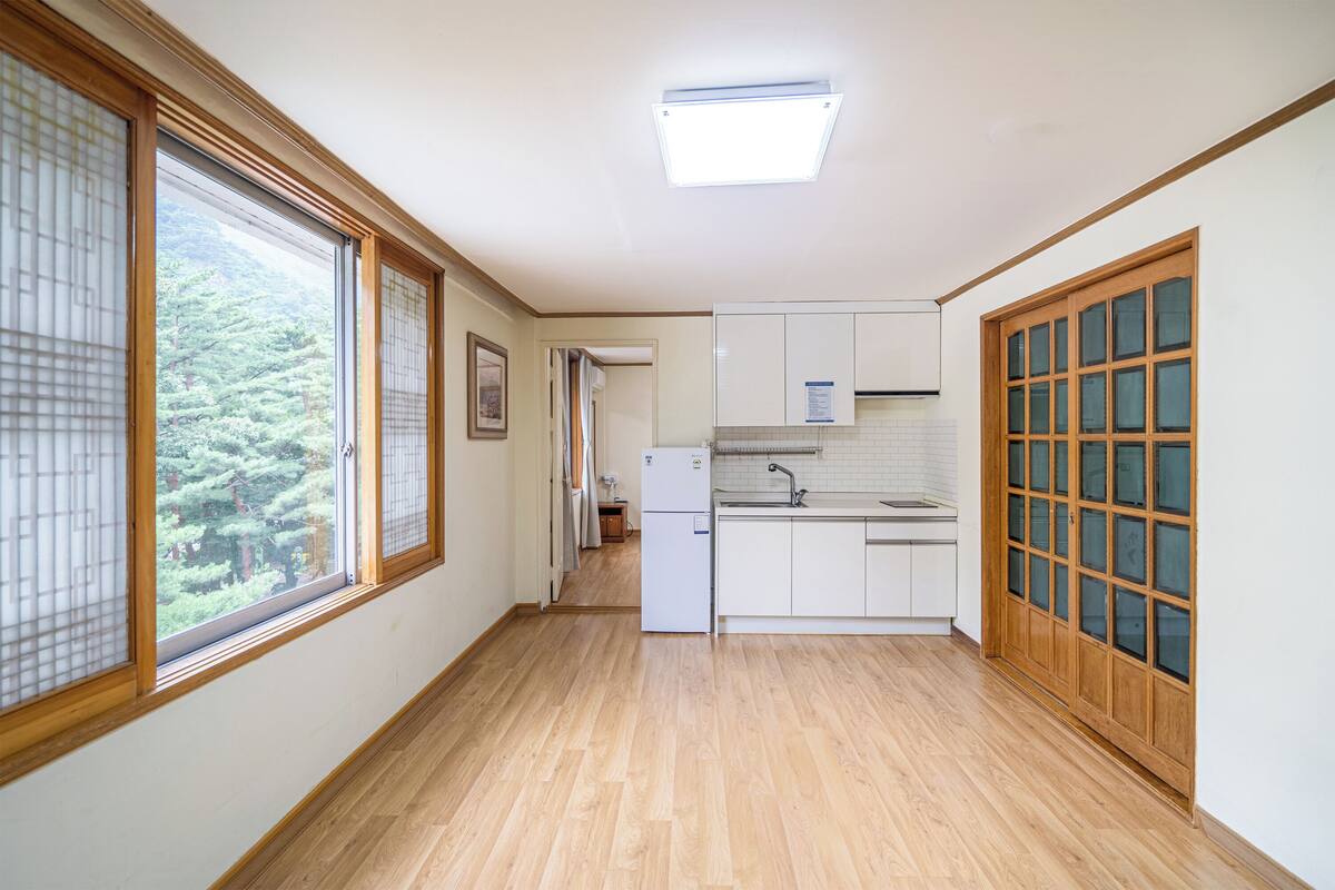 Ein schmaler Flur mit Holzboden, einem Kühlschrank und einem Spülbecken in einer kleinen Küchenzeile.