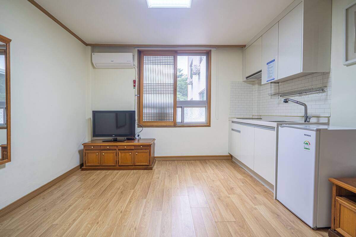 Eine Küche mit Holzausstattung, einem Backofen, einem Kühlschrank und einem Fenster mit Jalousien.