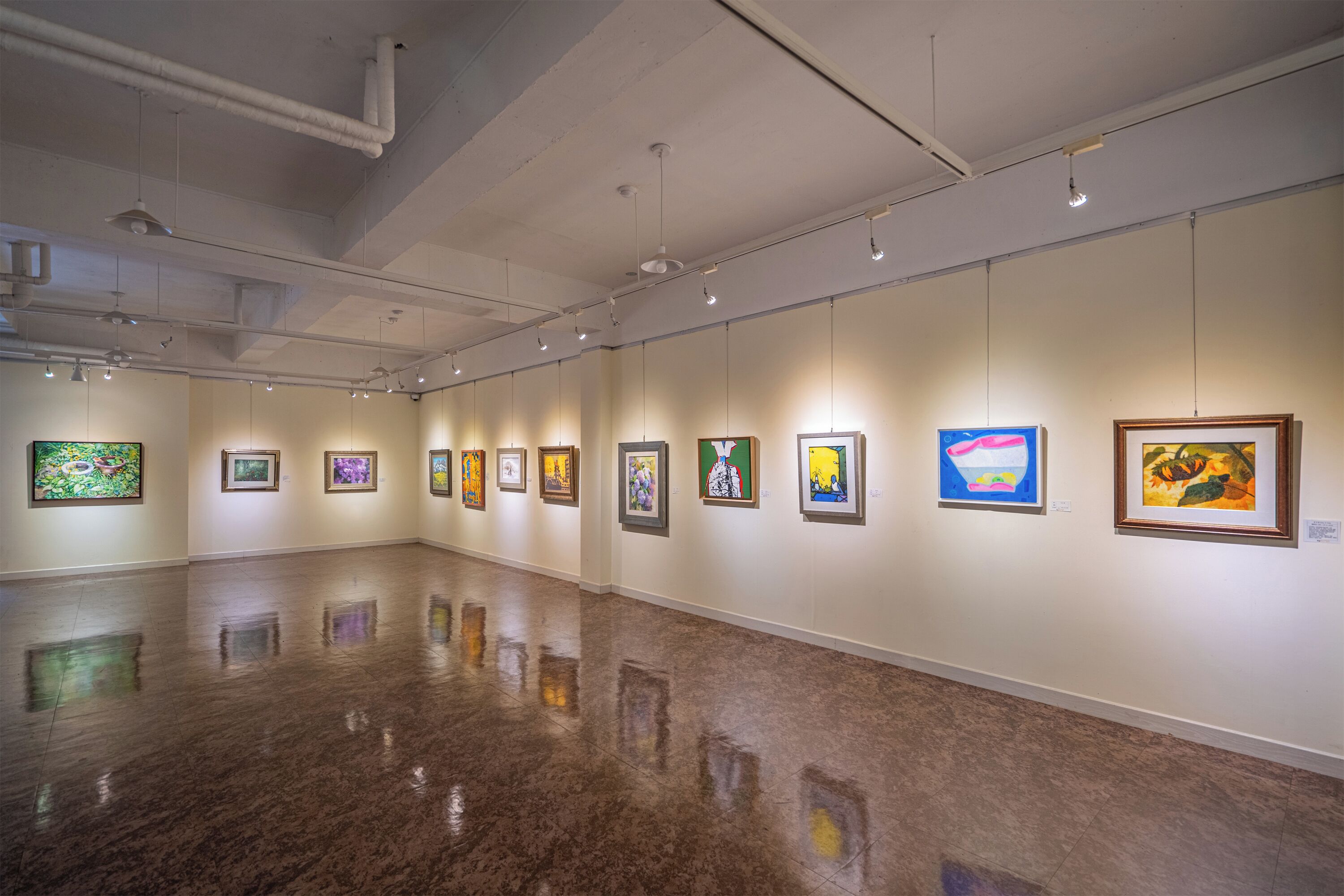 An art gallery with a polished floor and artworks displayed on the walls.