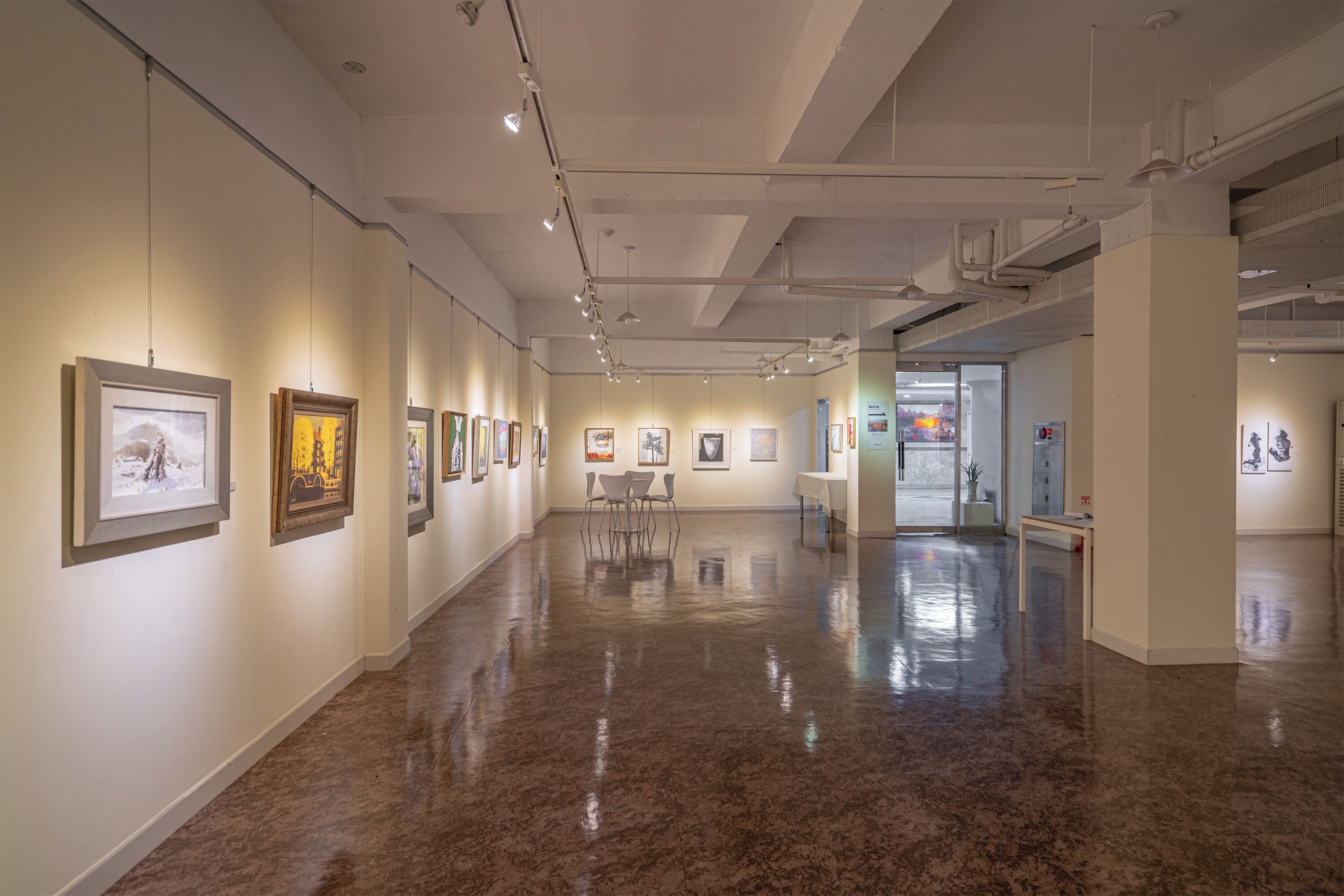 Una galería de arte con piso pulido y obras enmarcadas en las paredes.