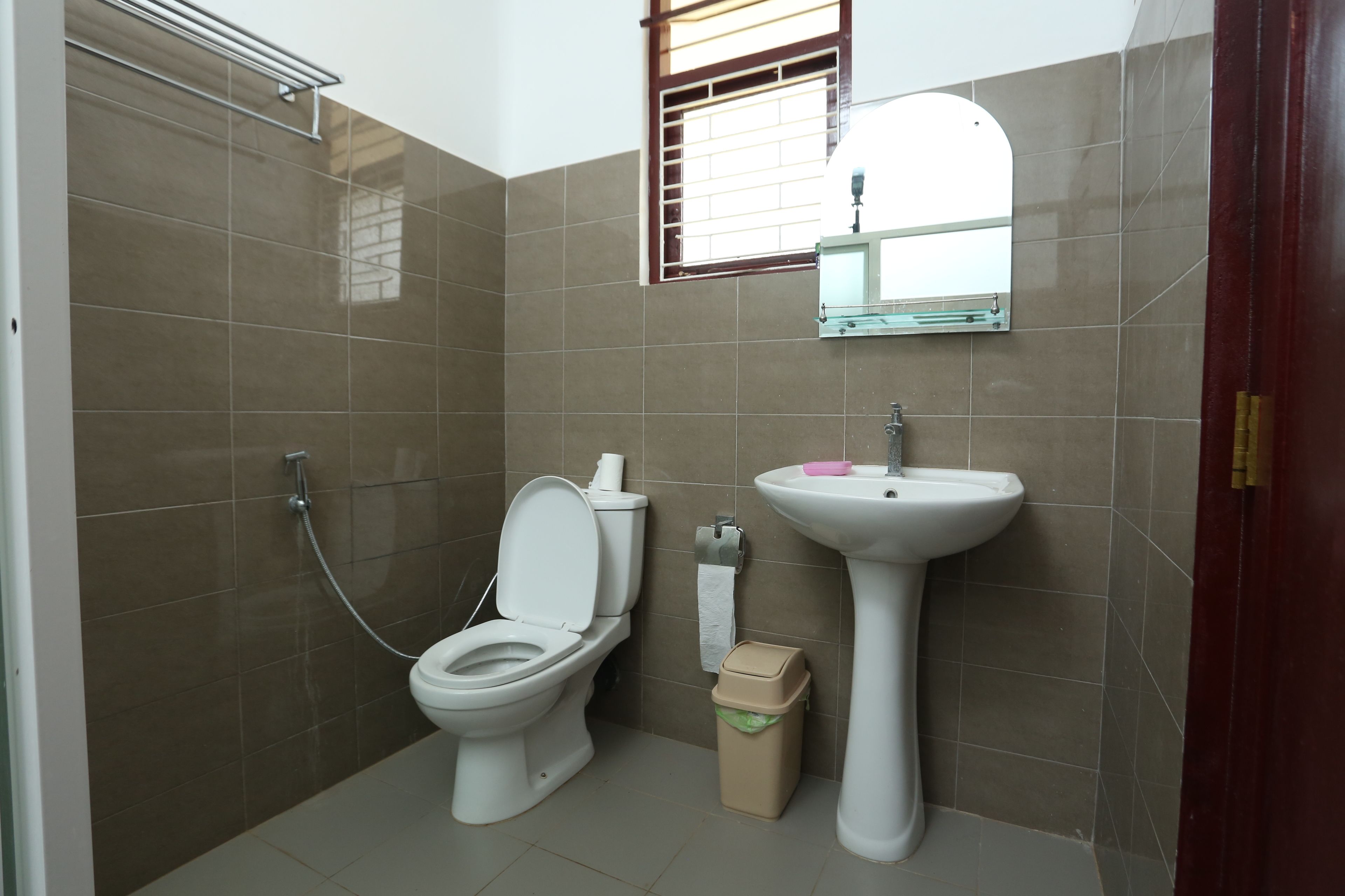 Un baño con inodoro, lavamanos y un cubo de basura.
