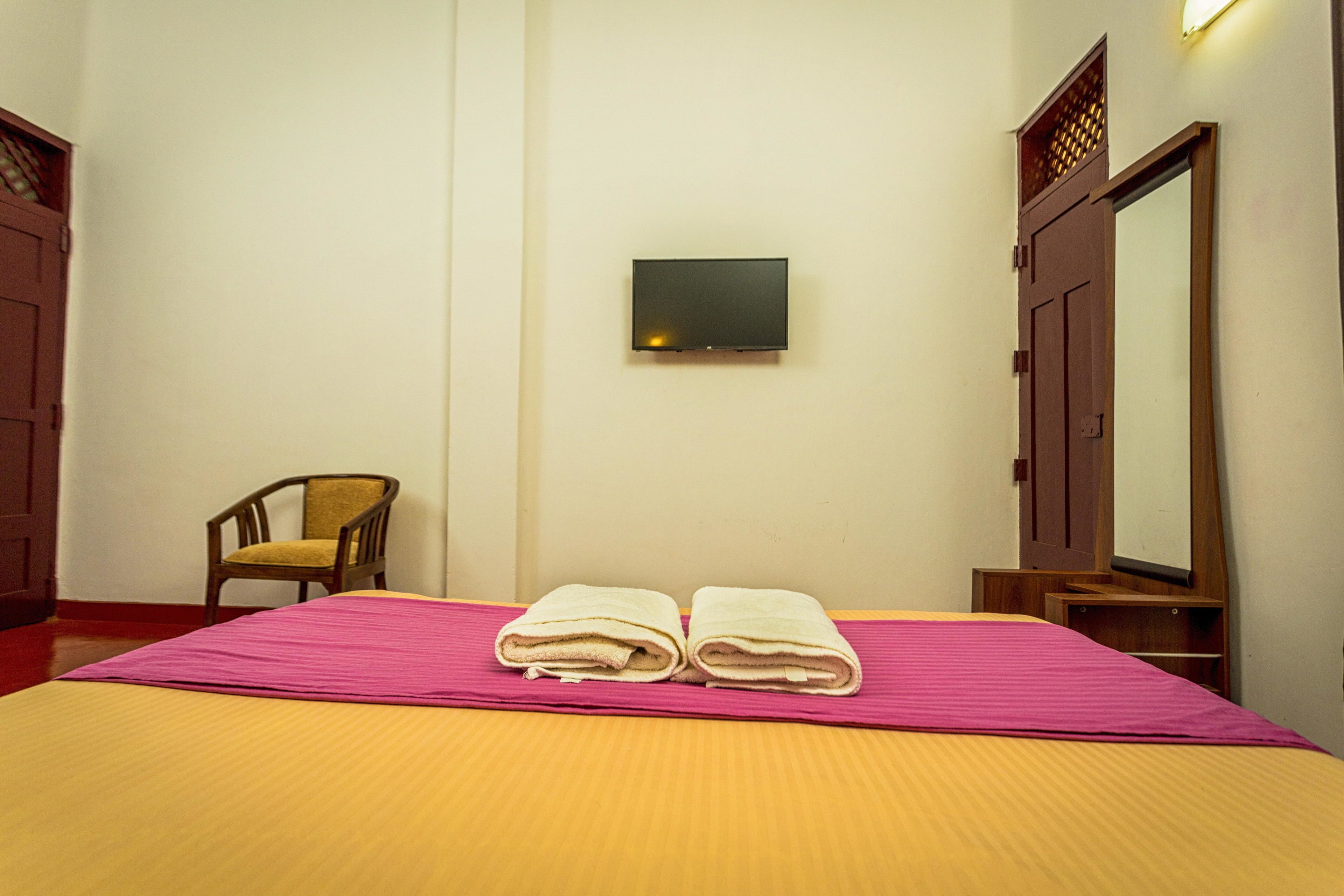 Una habitación de hotel con una cama, una silla, un televisor y un armario.