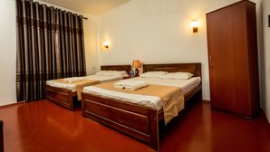 A hotel room with two wooden beds, a wardrobe, and a curtain.
