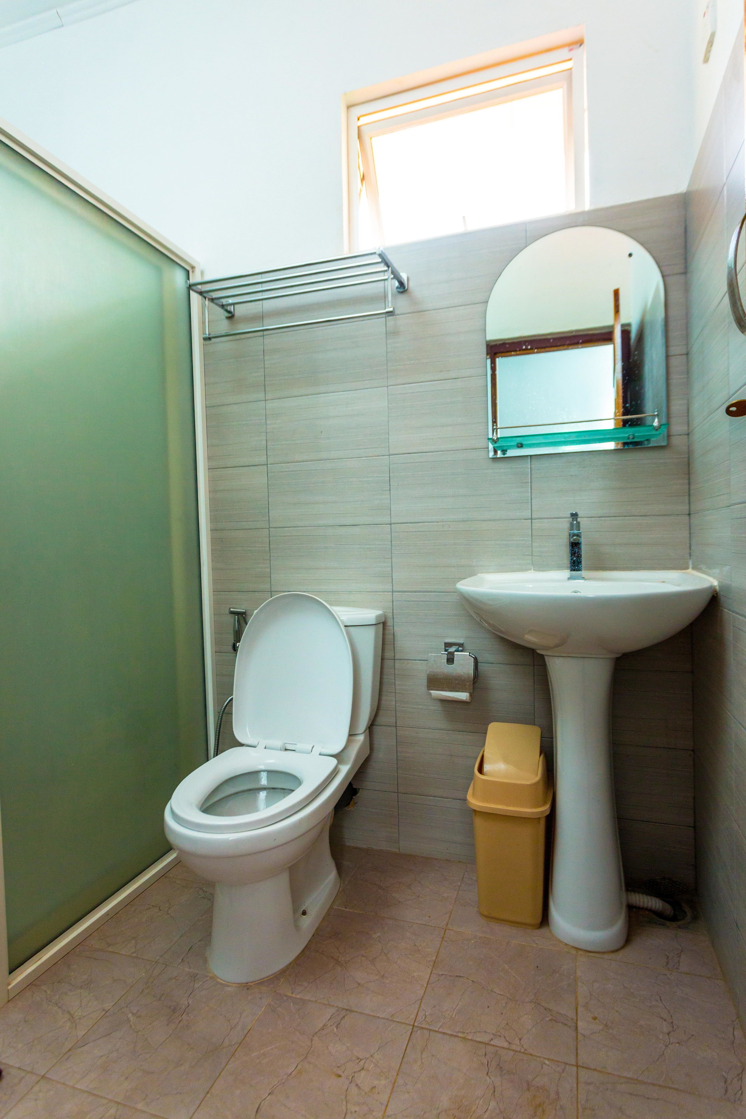 A bathroom with a toilet, sink, and a mirror above the sink.