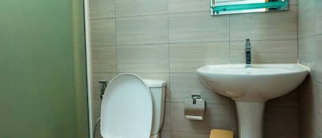 A bathroom with a toilet, sink, and a mirror above the sink.