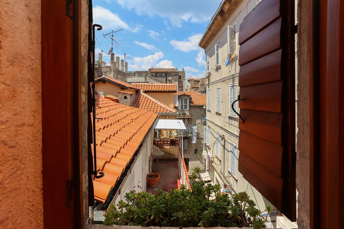 Un carrer estret amb terrasses de teules i vista d'edificis veïnals.