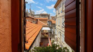A narrow alleyway with terracotta-tiled roofs and a view of adjacent buildings.