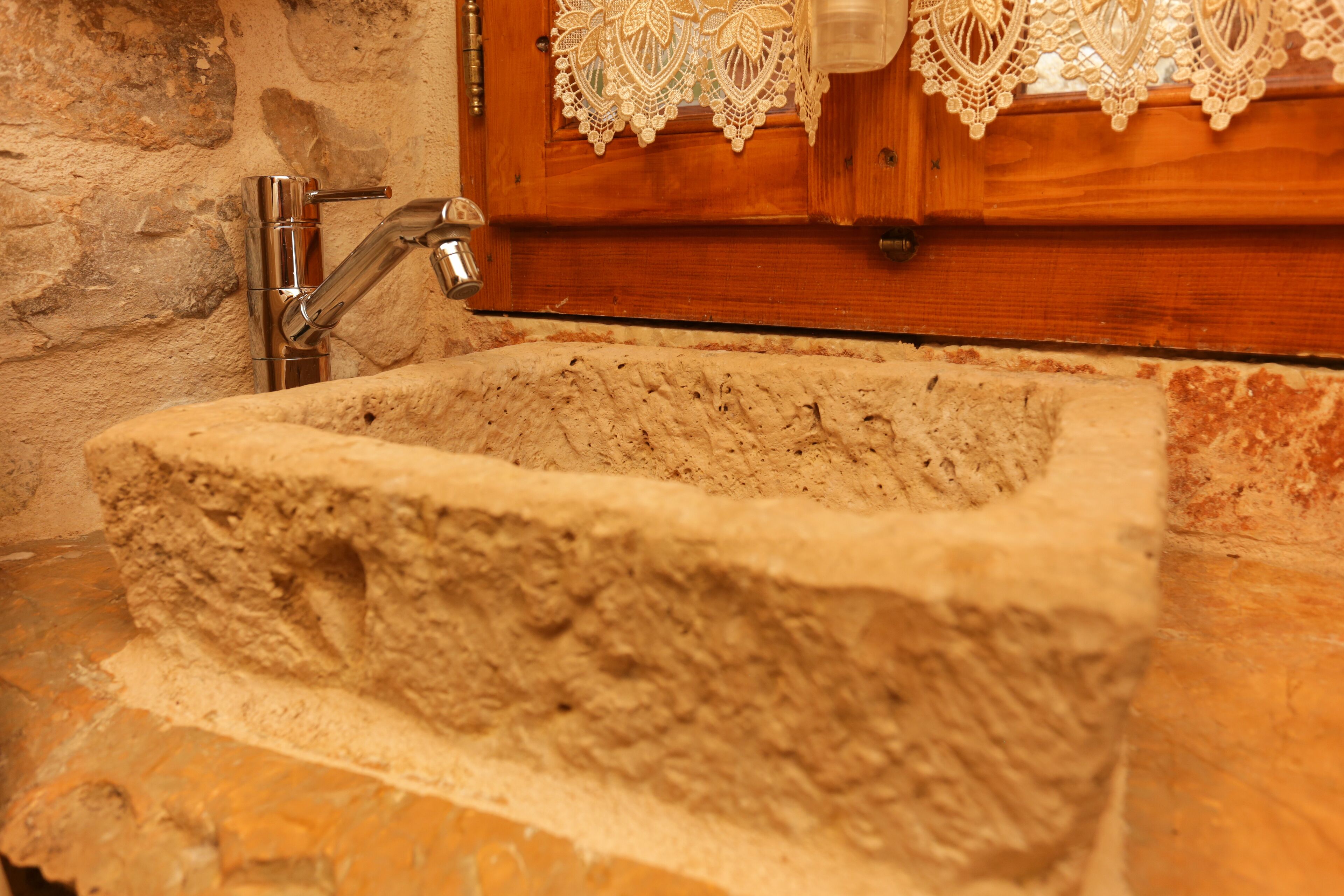 A stone sink with a wooden frame and lace decorations.