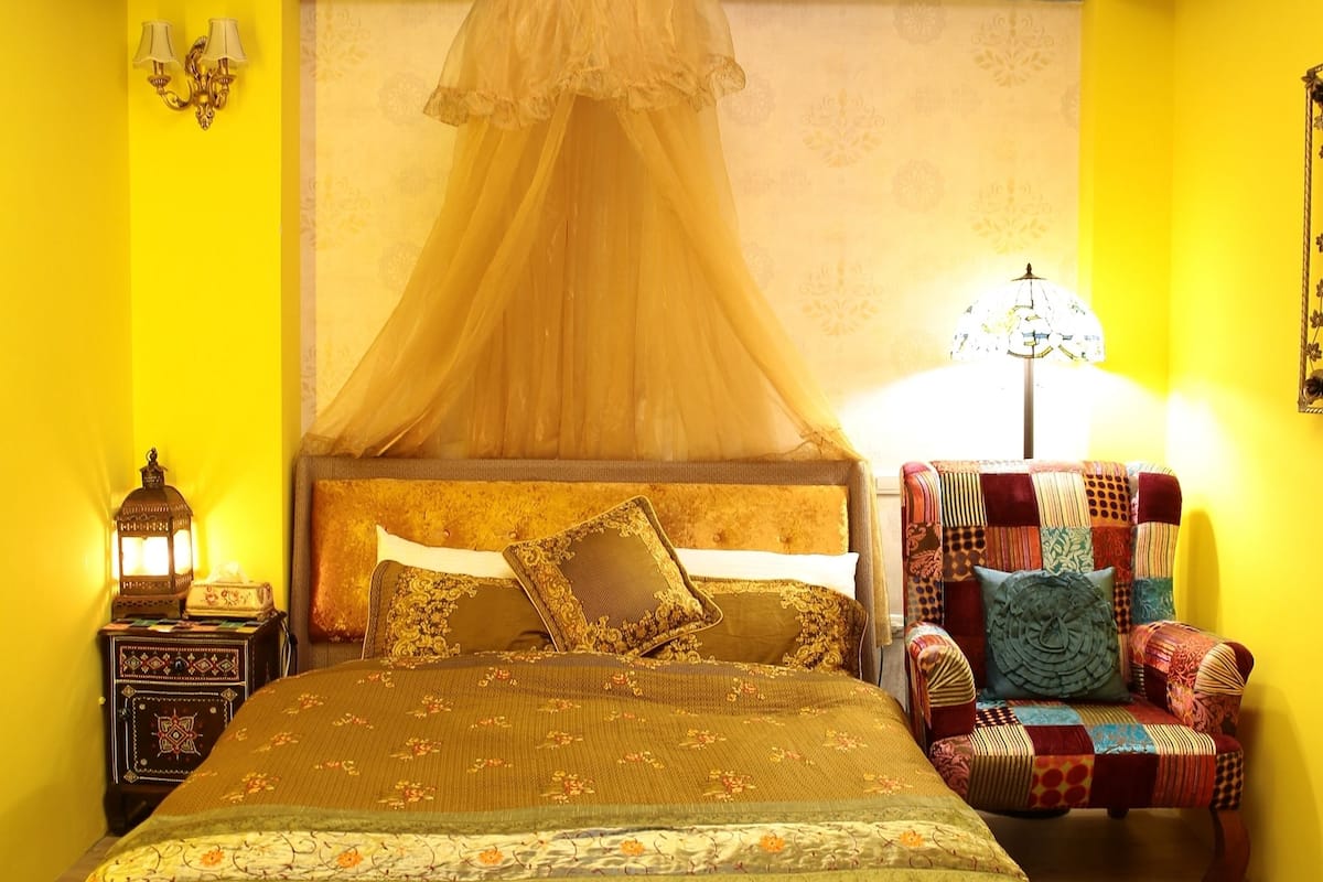 Un dormitorio con cama, una silla, una mesita de noche y una araña.