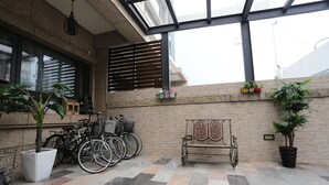 Un espacio al aire libre cubierto con piso a cuadros, bicicletas, un banco y plantas en macetas.
