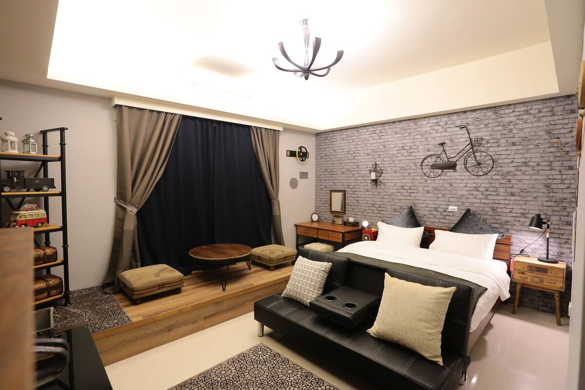 Un dormitorio moderno con una cama, un sofá, una mesita y una estantería.