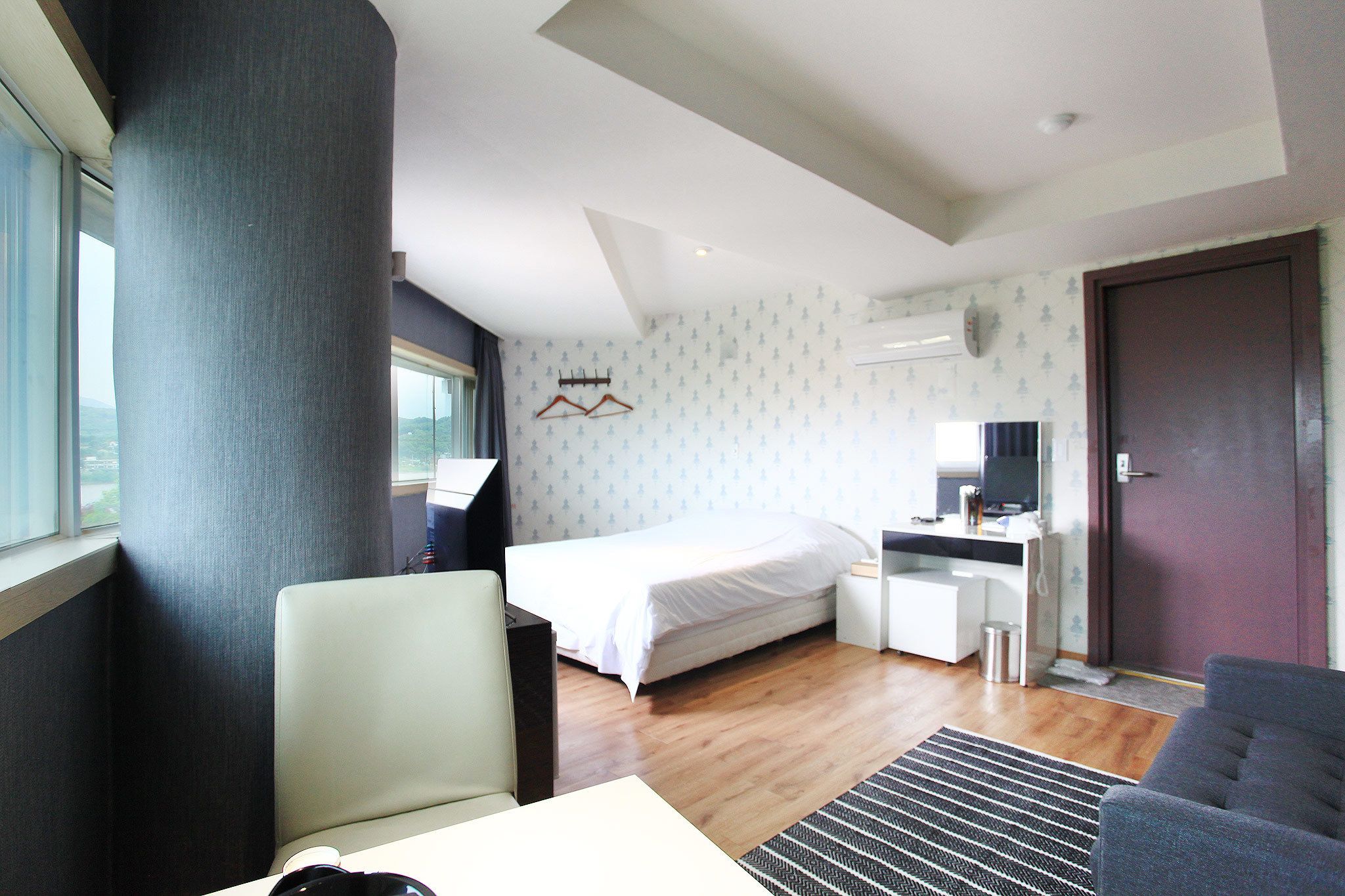 A hotel room with a bed, a desk, a chair, a TV, and a window.