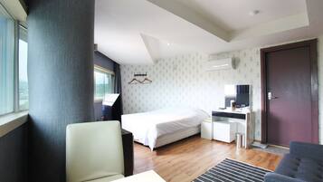 A hotel room with a bed, a desk, a chair, a TV, and a window.