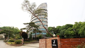 A hotel with a unique spiral architecture, a brick entrance, and a sign indicating it offers coffee and espresso. - J hotel (Yangpyeong)