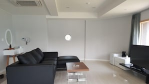 A modern living room with a black leather sofa, a wooden coffee table, a flat-screen TV, and a minimalist design. - J hotel (Yangpyeong)