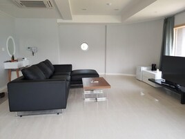 Una sala de estar moderna con un sofá de cuero negro, una mesa de centro de madera, un televisor de pantalla plana y un diseño minimalista.