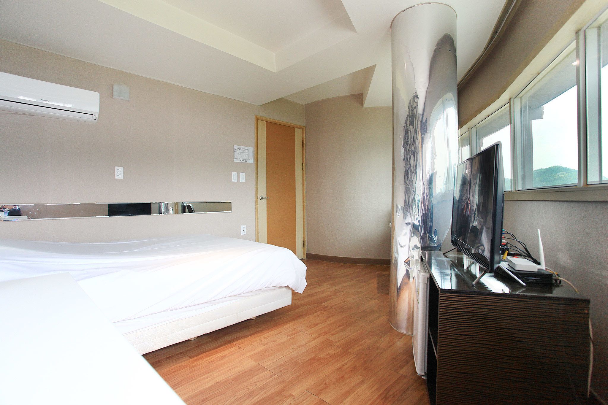 Una habitación de hotel con una cama, un televisor de pantalla plana y un ventanal con vistas.