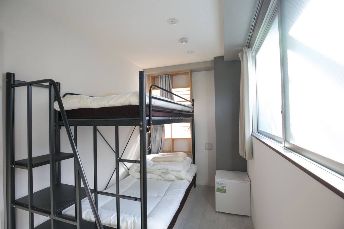 A bunk bed room with a window, a small desk, and a radiator.